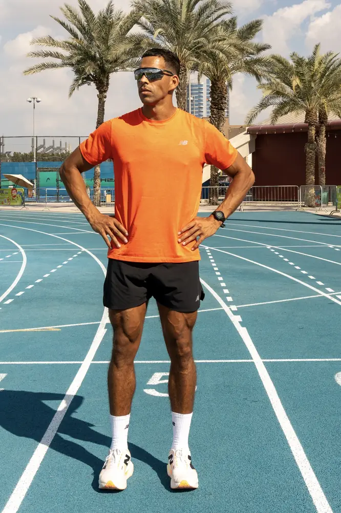 Runner standing on an athletics track among palm trees